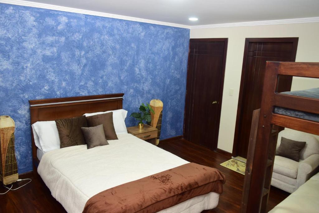 Hostería La Travesía Campiña في كوينكا: غرفة نوم بسرير وجدار ازرق