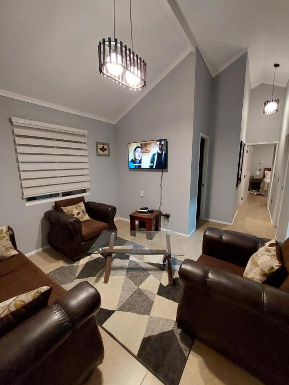sala de estar con muebles de cuero y TV de pantalla plana en Casa Isabella en Puerto Natales