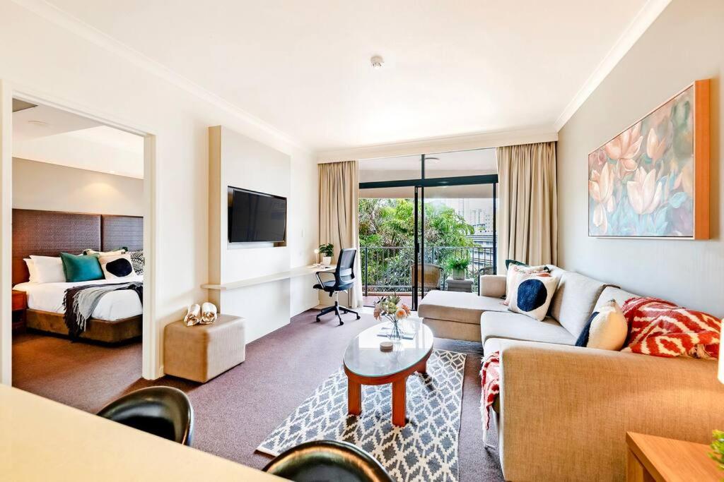 a living room with a couch and a bed at Poolside Resort Living on Esplanade with Balcony in Darwin