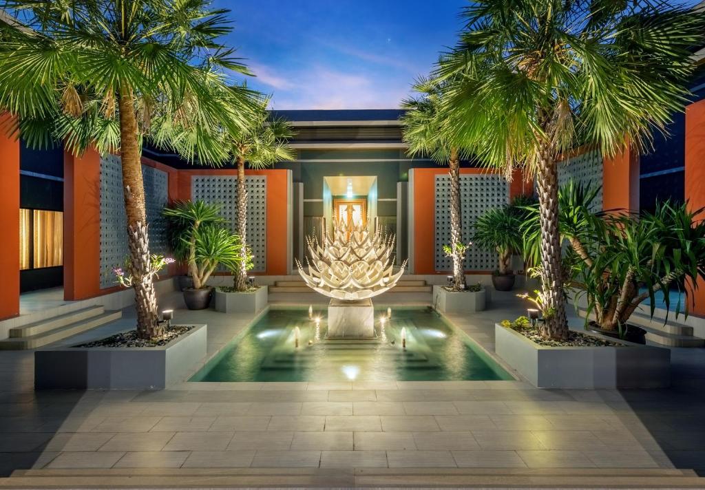 a temple with palm trees and a lit uporah at Phukalini Luxury Pool Villa & Onsen-SHA Plus Certified in Hua Hin