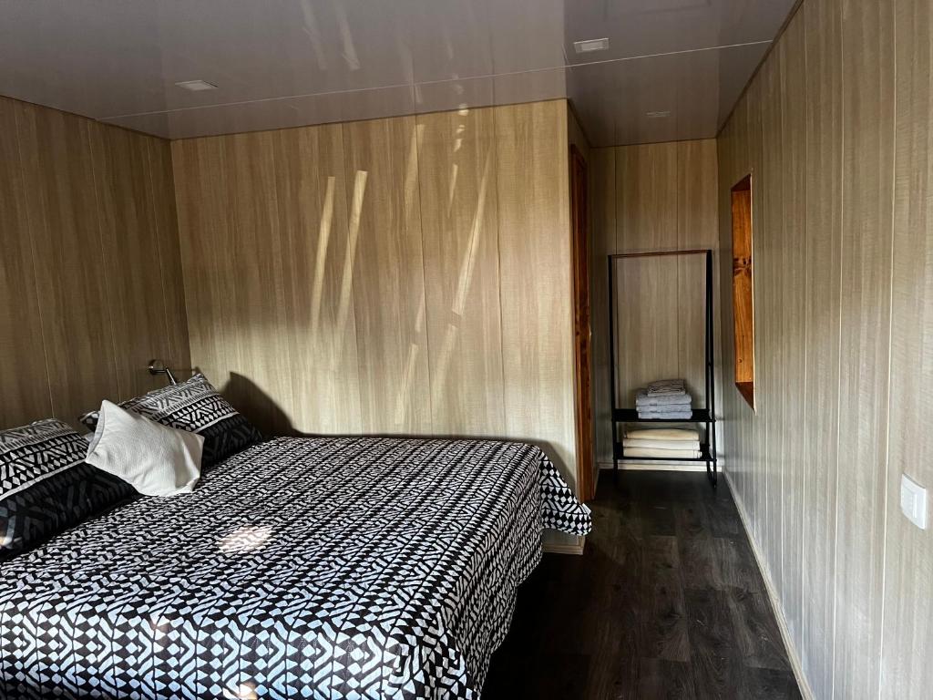 um quarto com uma cama em preto e branco e paredes de madeira em Alojamiento Rustico Belloto 1 em Quilpué