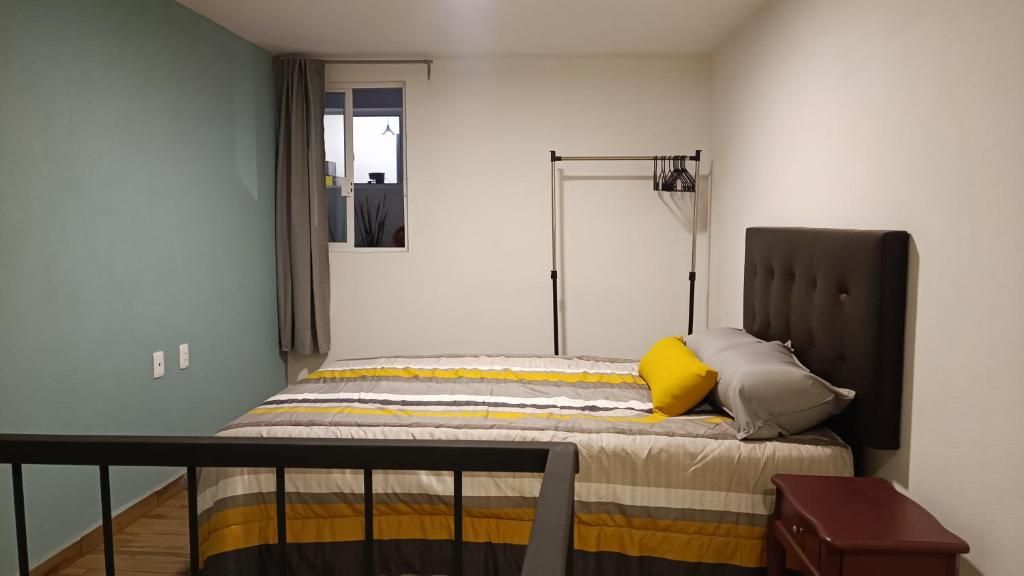 1 dormitorio con 1 cama con almohada amarilla en Departamento loft súper ubicado. en Orizaba