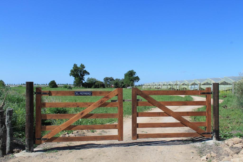 a wooden gate in front of a field at El Potrero Casa de Campo in Arana