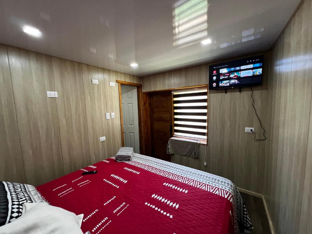 um quarto com uma cama e uma televisão de ecrã plano em Alojamiento rústico Belloto (3) em Quilpué