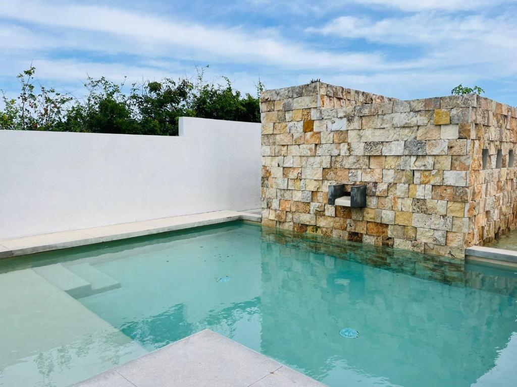 a swimming pool in front of a stone wall at Brand new penthouse with plunge pool, amazing top view in Isla Mujeres