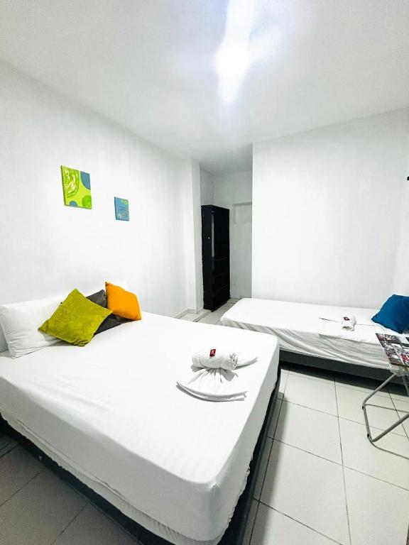 2 camas en una habitación con paredes blancas en Riviera Central Hotel, en Montería
