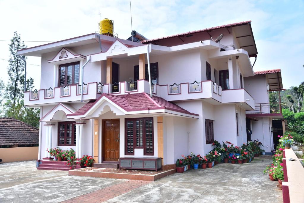 a white house with flowers in front of it at Madhuvana Homestay Coorg in Madikeri
