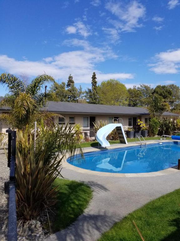 een zwembad met een glijbaan naast een huis bij Tasman Motor Camp in Tasman