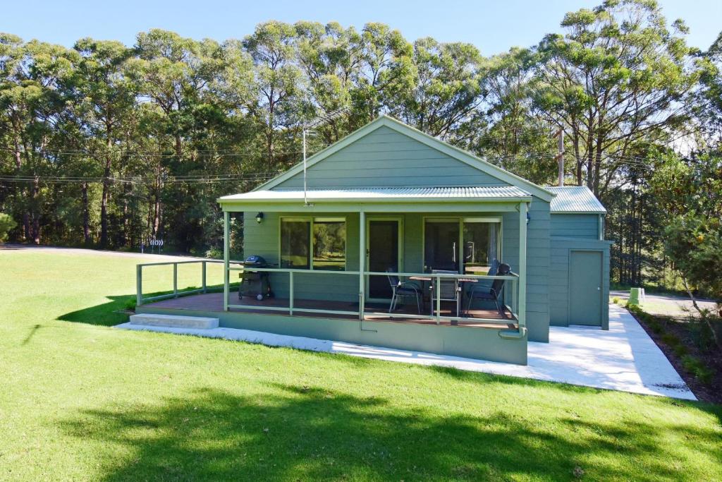 a small blue house with a patio in a yard at Beau Villa - Two bedroom Villa on golf course in Kangaroo Valley