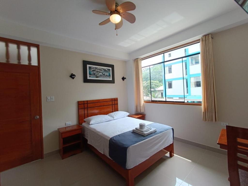 a bedroom with a bed with a ceiling fan and a window at Hotel Inambari Golden in Chiforongo