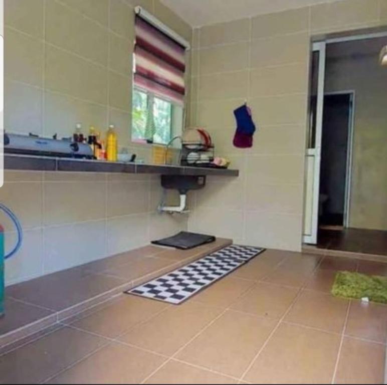 uma cozinha com um balcão, um lavatório e piso em azulejo em Teratak Kayu Homestay em Batu Pahat