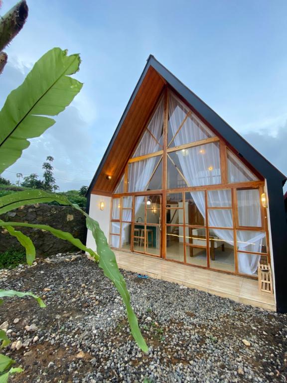 uma casa de vidro com um telhado preto em Martos villa dieng em Diyeng