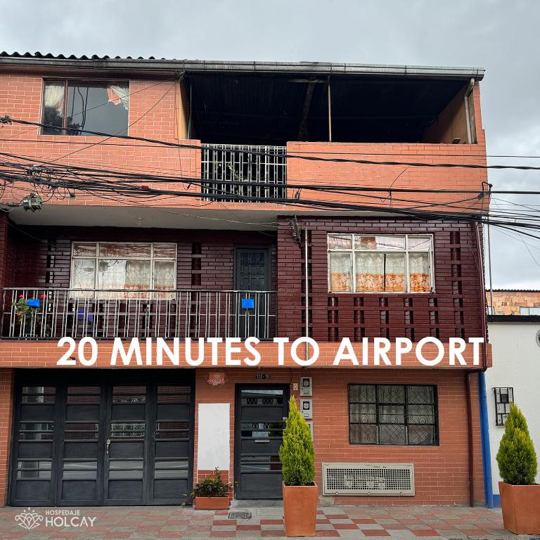 a building with a sign that reads minutes to airport at Hospedaje Holcay in Bogotá