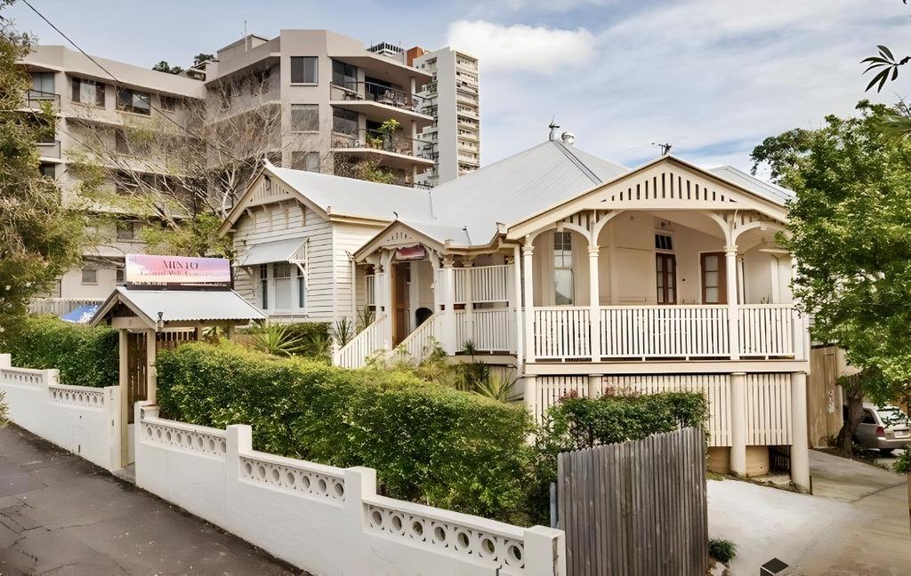une maison blanche en face d'un grand bâtiment dans l'établissement Minto Accommodation Brisbane, à Brisbane