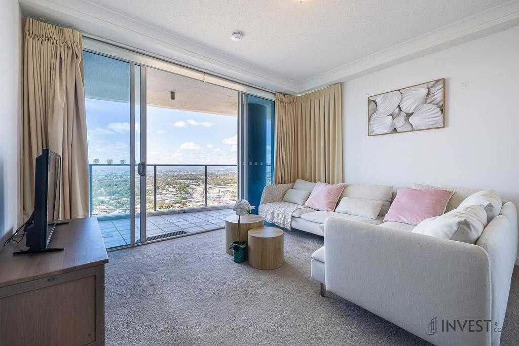 uma sala de estar com um sofá branco e uma televisão em Gorgeous 2BR Apt with City & Water views Southport em Gold Coast