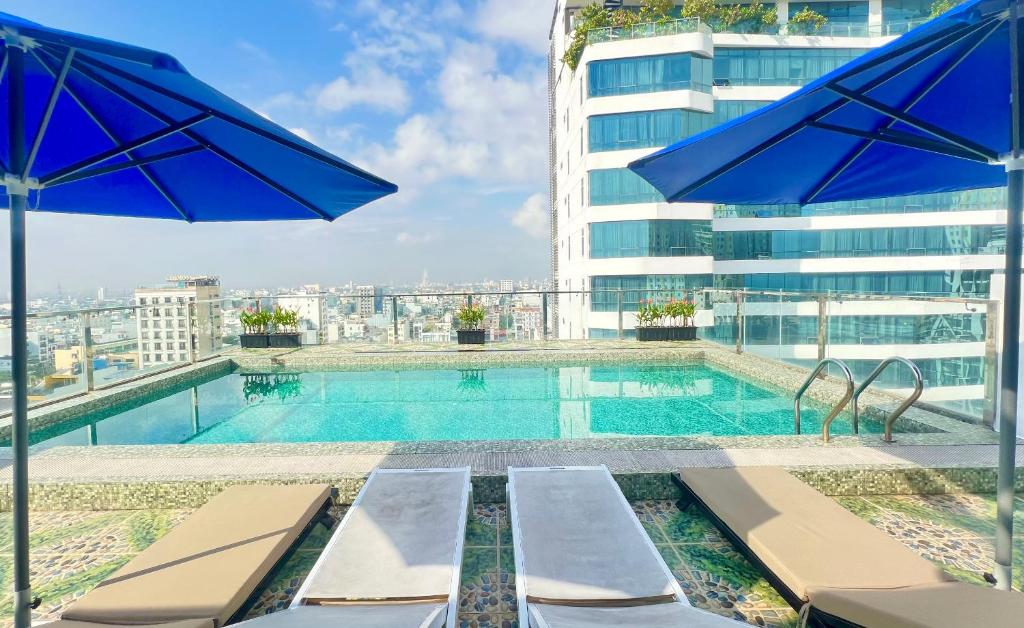 A rooftop pool overlooks the city, with blue umbrellas and loungers along the near edge.