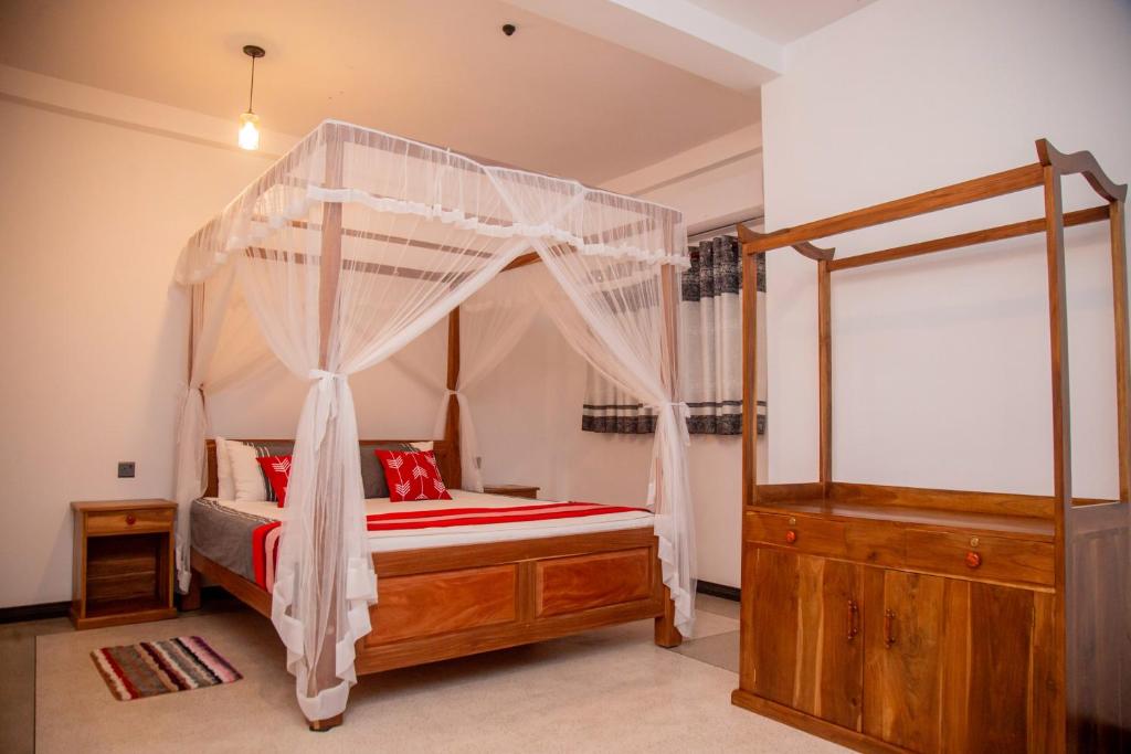 ein Schlafzimmer mit einem Himmelbett und roten Kissen in der Unterkunft Eden Sea View in Talpe