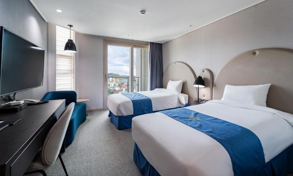 Habitación de hotel con 2 camas y TV de pantalla plana. en Golden Tulip Essential Namgang, en Jinju