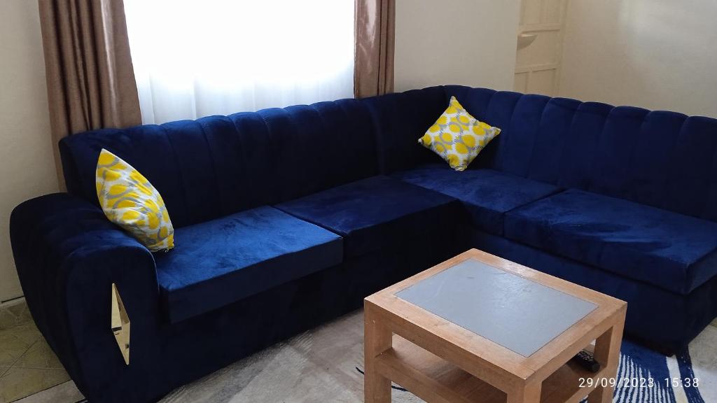 a blue couch with yellow pillows and a coffee table at Joyful homes Air Bnb in Naivasha