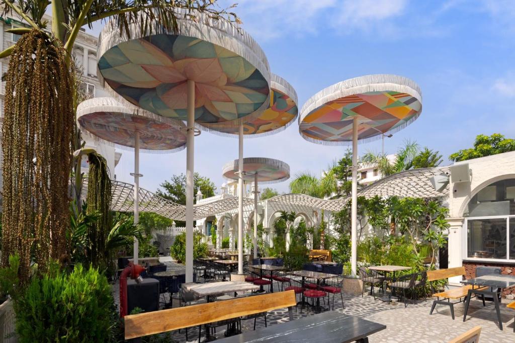 a patio with tables and chairs and umbrellas at DYORE House by Bharat Mahal Palace in Jaipur