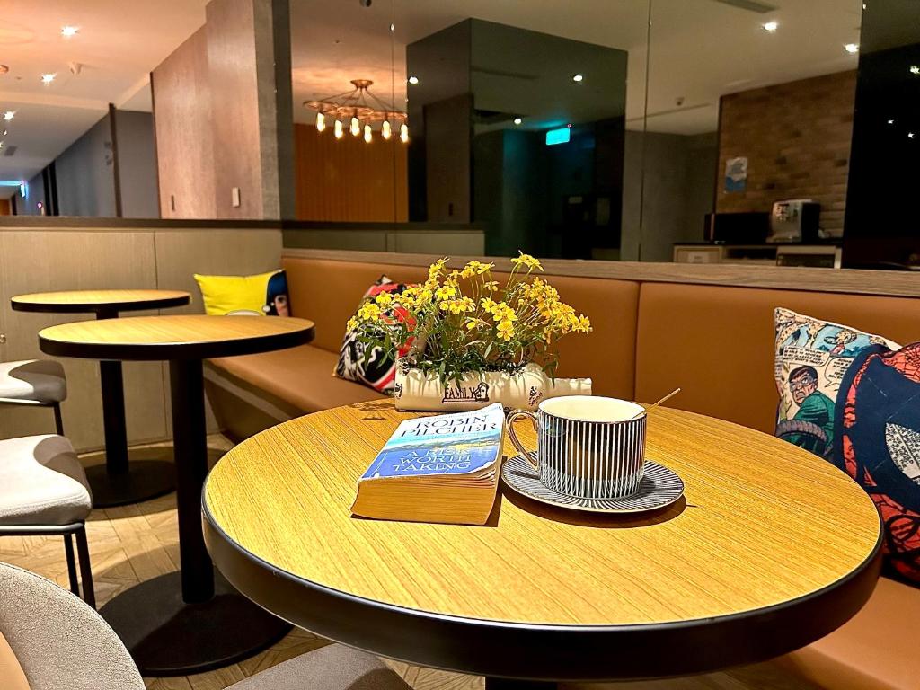 a table with a cup of coffee and flowers on it at Fun Stay Inn Ximen in Taipei