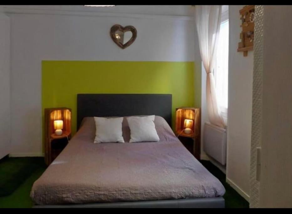 a bedroom with a green wall with a bed and two lights at COTE PORT T2 vue port centre ville Bandol in Bandol