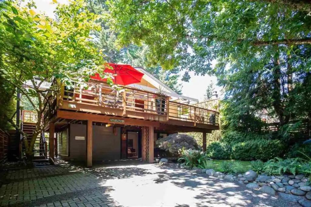 a house with a deck with a red umbrella at Cozy Snug Cove Treehouse in Bowen Island