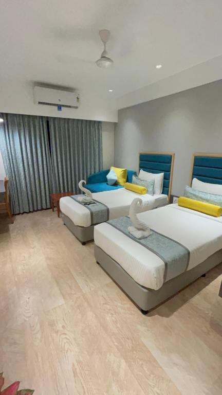 a room with three beds in it at Hotel The Excellency in Surat