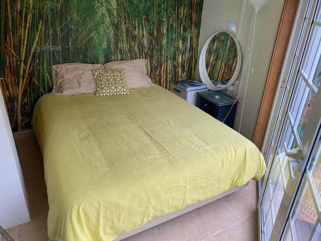 a bed with a yellow comforter in a bedroom at Amazigh Guincho Hostel & Suítes in Cascais