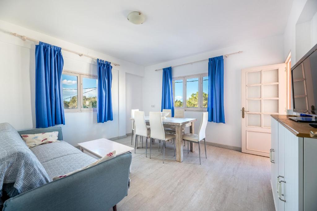 a living room with a couch and a table with chairs at Apartamento los Hermanos in Es Pujols