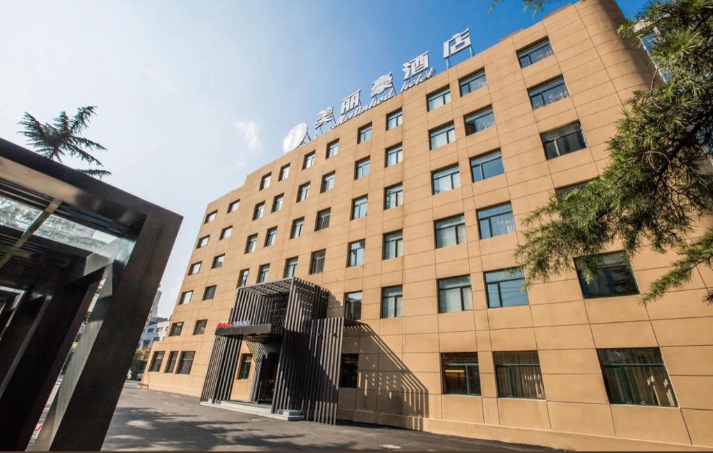 a large building with a staircase in front of it at Mehood Hotel Dalian Hi-tech Wanda Plaza Xinghai in Dalian