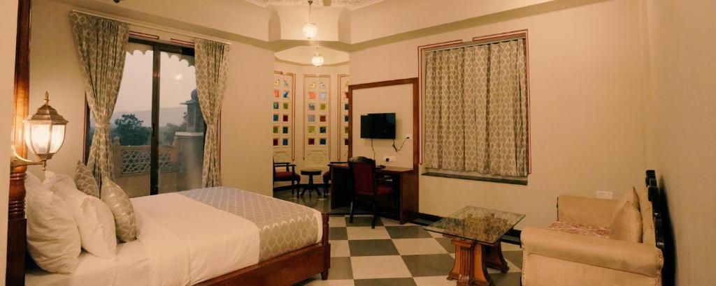 ein Hotelzimmer mit einem Bett und einem Wohnzimmer in der Unterkunft The Biletha Bagh in Udaipur