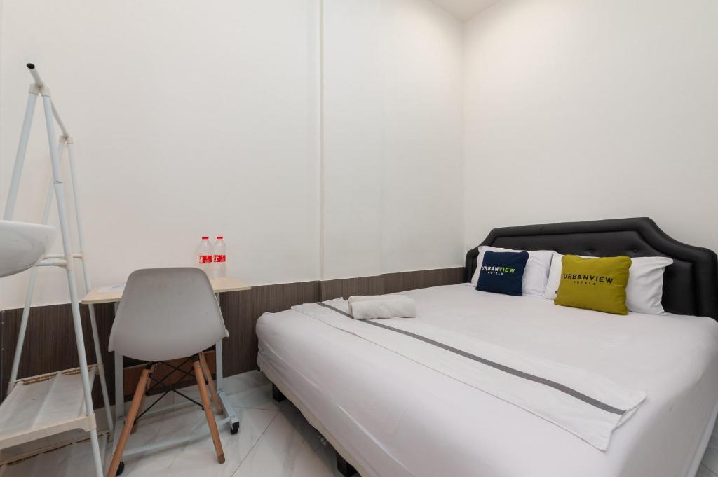 een slaapkamer met een bed, een bureau en een stoel bij Urbanview Hotel Kota Tua Jakarta in Jakarta