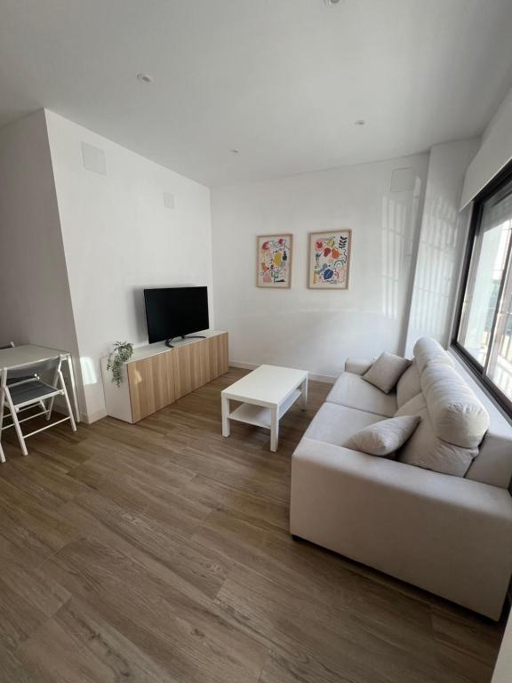 sala de estar blanca con sofá y TV en Casa Luz, en Montoro