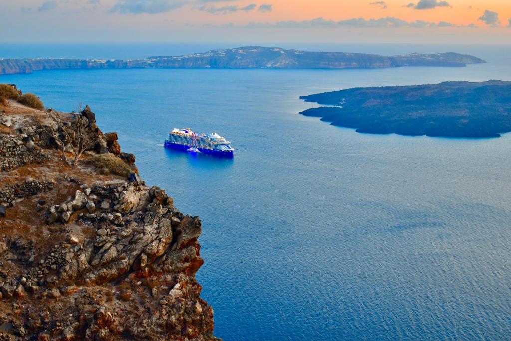 a large boat in a large body of water at Aeolos Art & Eco Suites Adults Only in Imerovigli