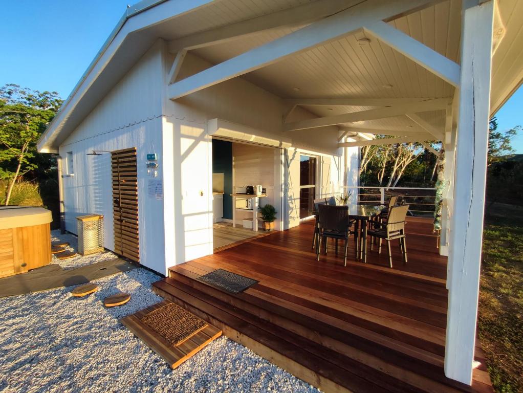 una terrazza in legno con tavolo e sedie. di NIAOULI LODGE a Bourail