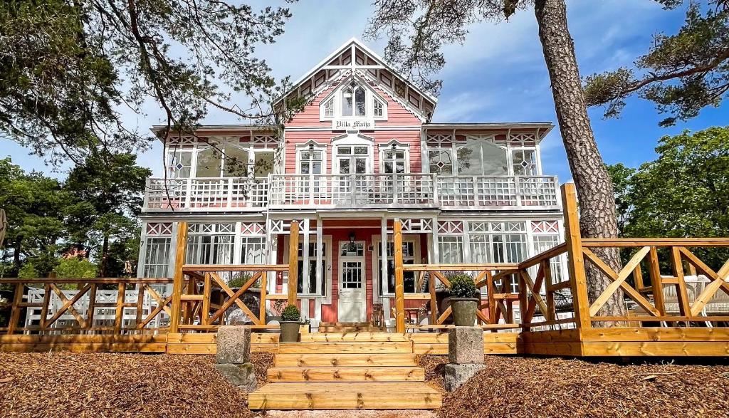a large pink house with a large deck at Villa Maija 1 Eastside in Hanko