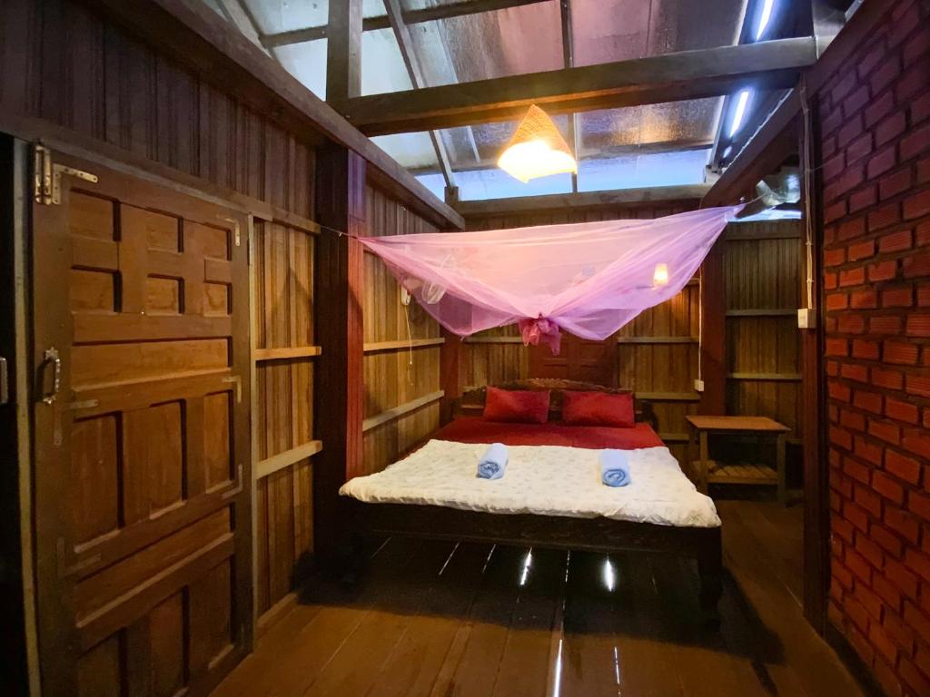 Zimmer mit einem Bett und einem Moskitonetz in der Unterkunft Backpacker Hostel and Jungle Trekking in Banlung