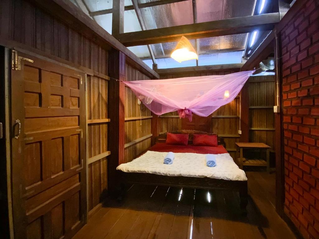 a room with a bed with a mosquito net at Backpacker Hostel and Jungle Trekking in Banlung
