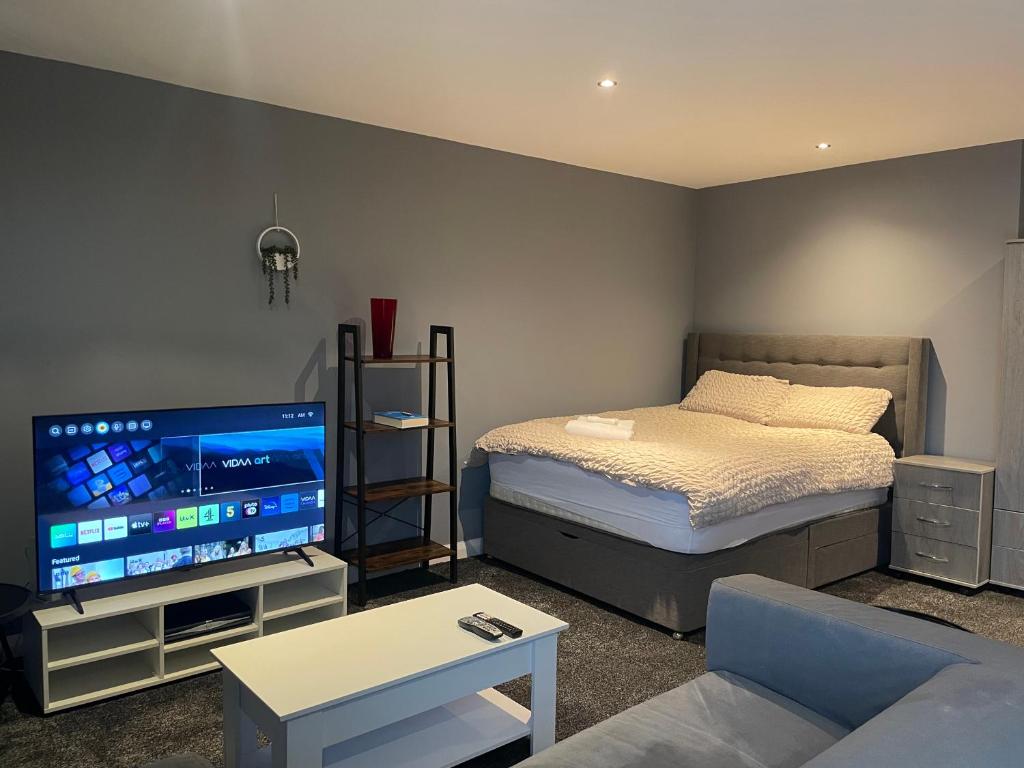a living room with a bed and a flat screen tv at Manchester Old Trafford CityView En-Suite Apt in Manchester