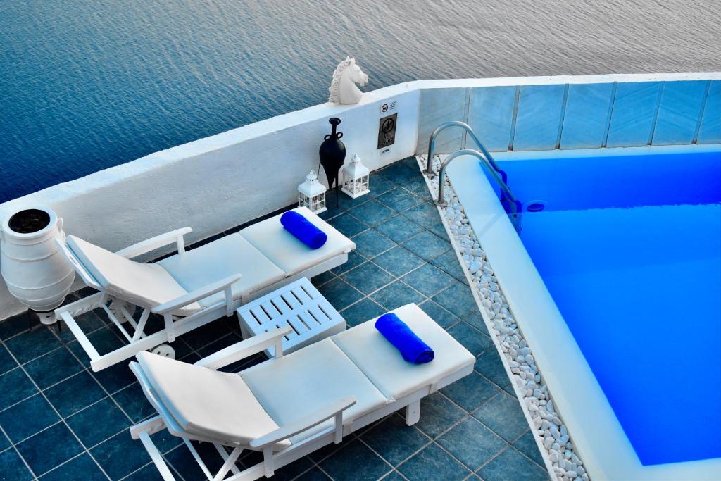 a swimming pool with two chairs and a swimming pool at Aeolos Art & Eco Suites Adults Only in Imerovigli