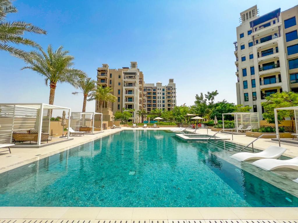 a large swimming pool with palm trees and buildings at FAM Living - Rahaal 1BR Bliss in Madinat Jumeirah Living in Dubai
