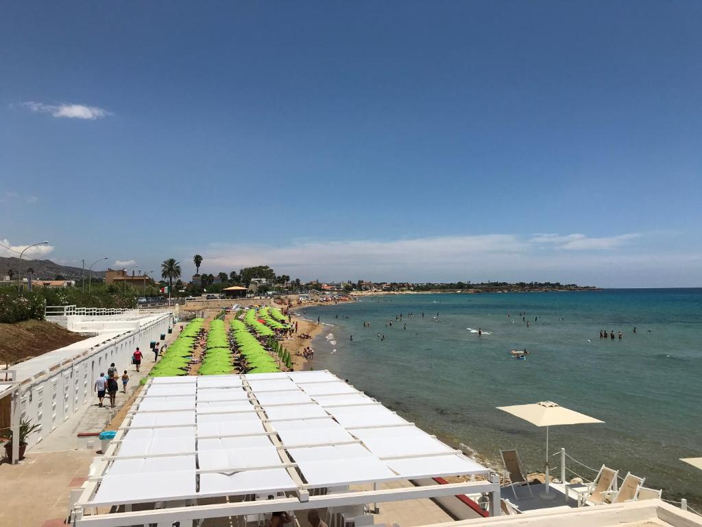 ein Strand mit weißen Sonnenschirmen und Menschen im Wasser in der Unterkunft Le Torrette Rooms and Apartments in Avola