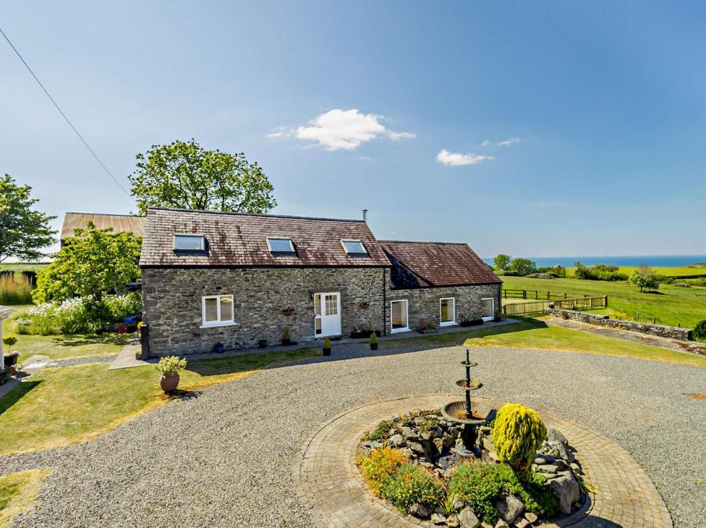 an old stone house with a garden in front of it at 4 Bed in Aberaeron 92072 in Llanrhystyd