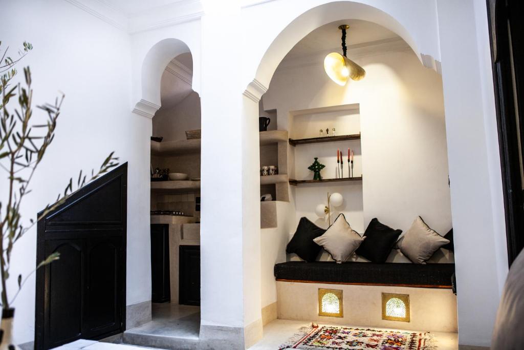 einen Flur mit weißen Wänden und einer schwarzen Bank mit Kissen in der Unterkunft Cosy Riad in Marrakesch