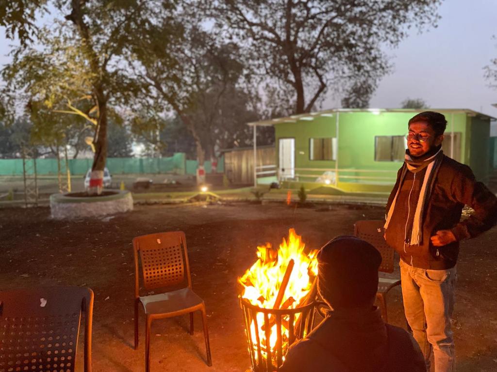 a man standing in front of a fire at Green Valley Family Resort in Amarkantak