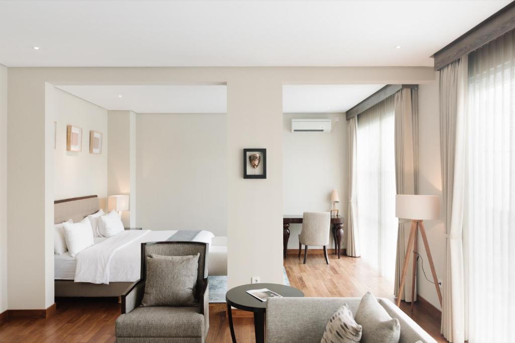 a bedroom with a bed and a chair and a couch at Kula Kara Villas Uluwatu in Uluwatu