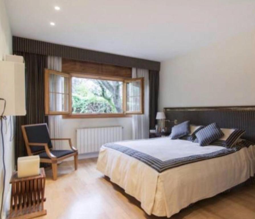 een slaapkamer met een bed, een stoel en een raam bij Preciosa habitación en suite in Algete