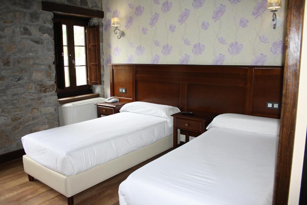a room with three beds and a wall with flowers at Hotel Rural El Reundu in Campomanes