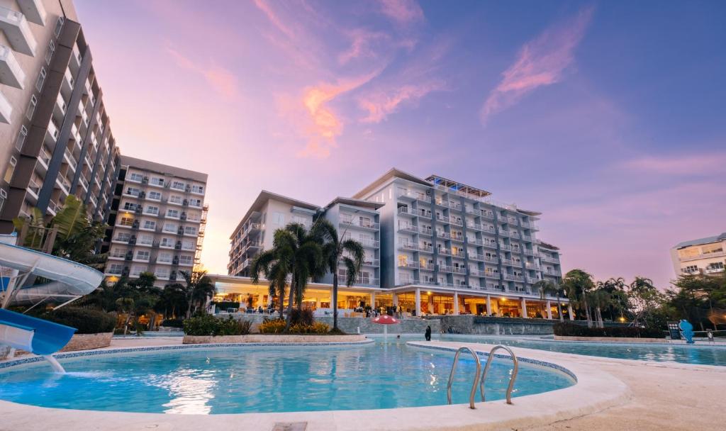 a hotel with a pool in front of buildings at Solea Mactan Resort in Mactan